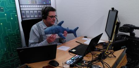 padeluun hält einen Online-Vortrag – in seinen Händen streckt er einen Plüschhai Richtung Webcam.